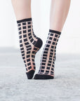 chaussettes transparentes à carreaux noirs pied pointé sur fond gris