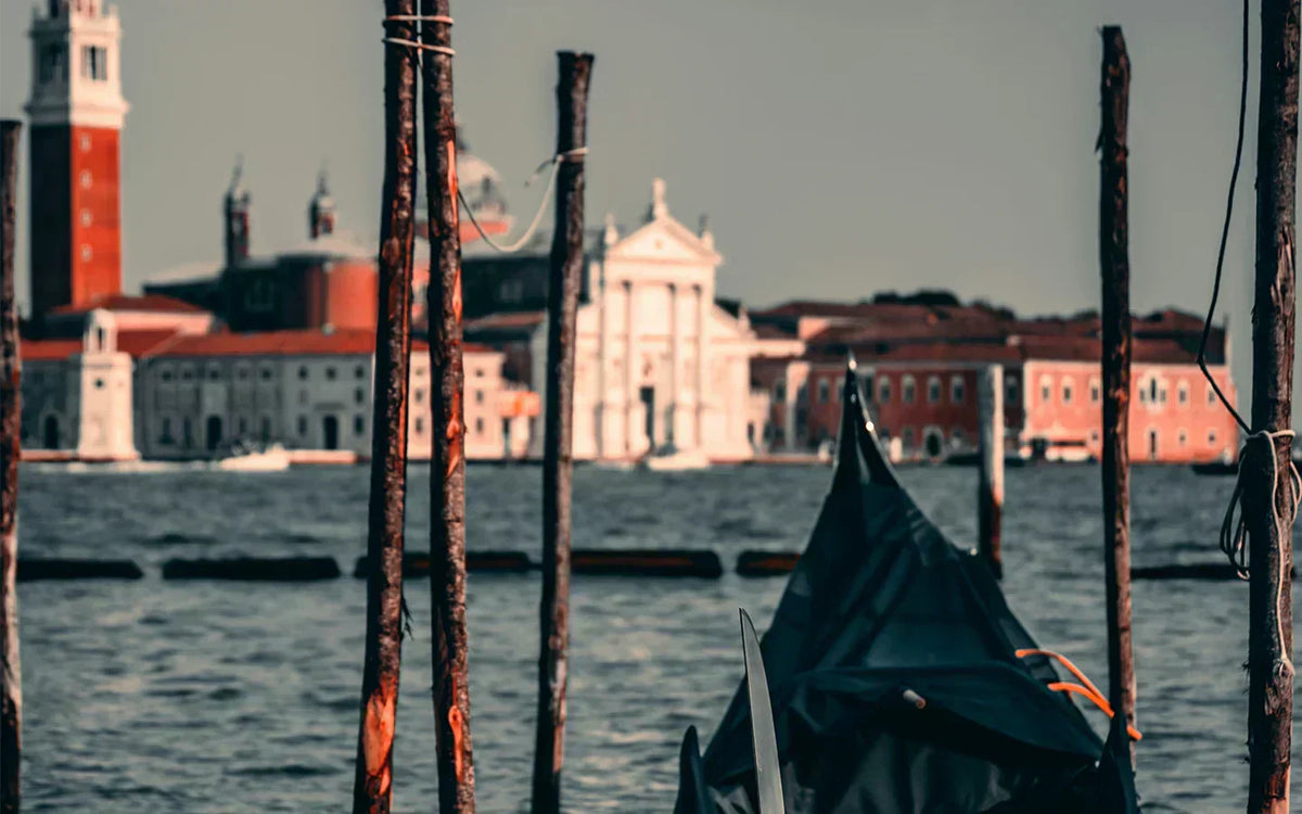 Photographie de la ville de Venise, montrant l'architecture de la ville en arrière plan et une gondole au premier plan. 